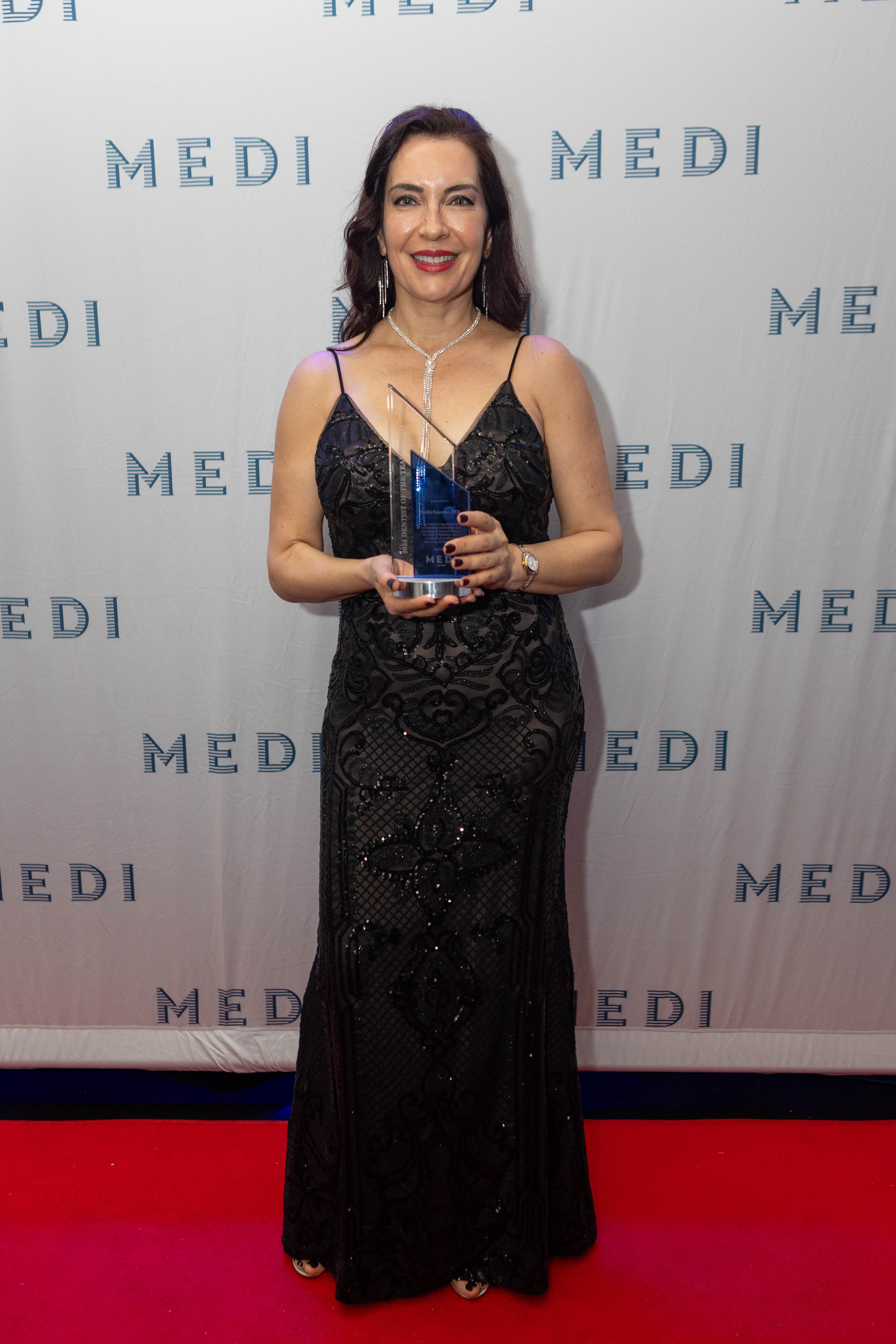 Dr. Paola Kesman holding her 2024 Dentist of the Year award